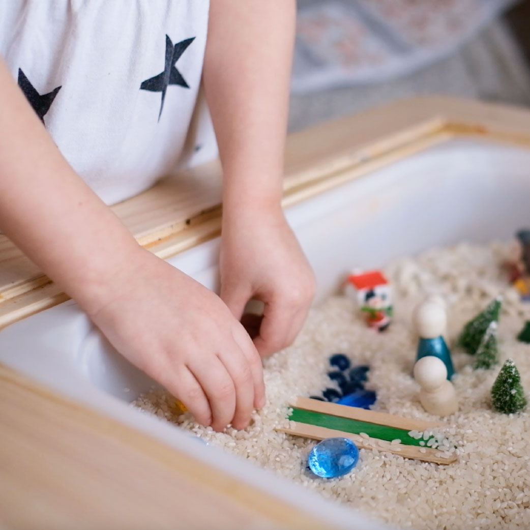 young girl playing with toys in rice