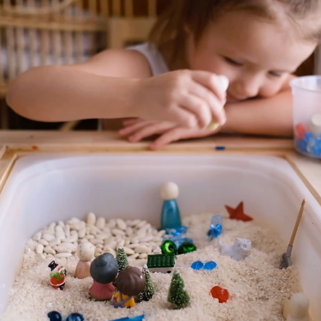 young girl playing with toys in rice